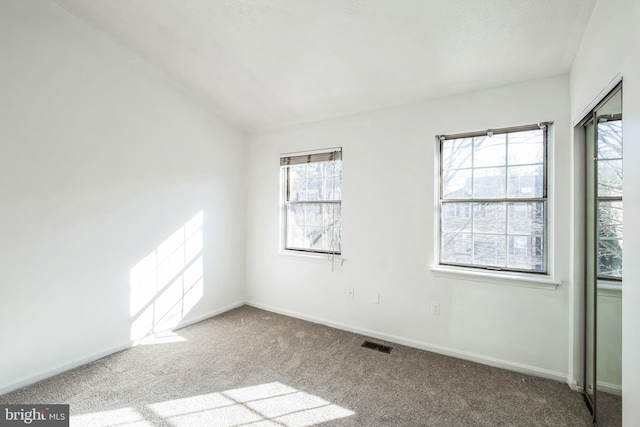 carpeted empty room featuring vaulted ceiling