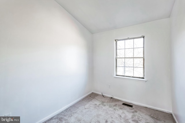 carpeted empty room featuring lofted ceiling