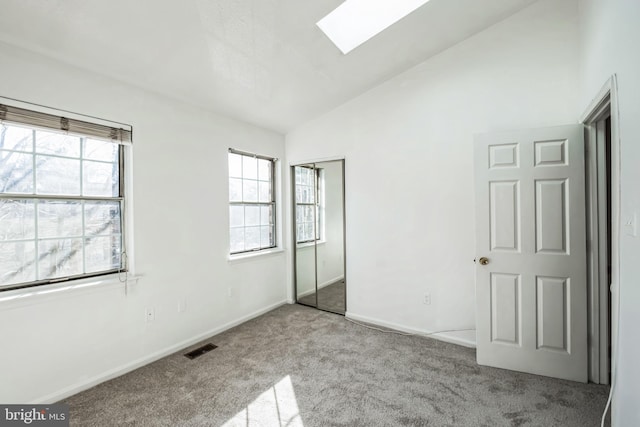 unfurnished bedroom featuring lofted ceiling with skylight and light carpet