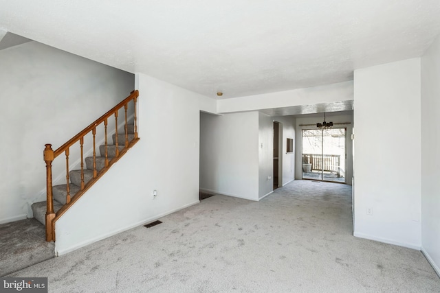 spare room featuring an inviting chandelier and light colored carpet