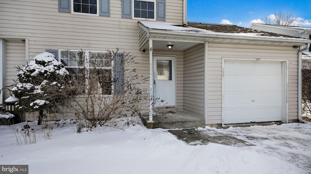 snow covered property entrance featuring a garage