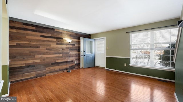 unfurnished room with hardwood / wood-style flooring and wooden walls