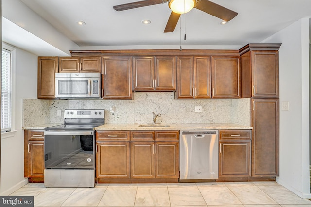 kitchen with sink, light tile patterned floors, light stone countertops, and stainless steel appliances