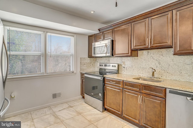 kitchen featuring decorative backsplash, sink, stainless steel appliances, light stone counters, and light tile patterned flooring