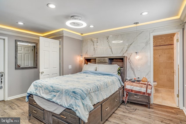 bedroom with connected bathroom, ornamental molding, and light wood-type flooring