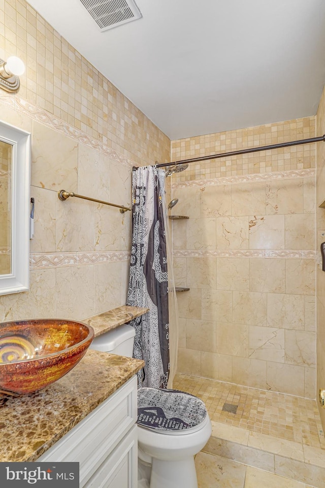 bathroom with toilet, vanity, a shower with shower curtain, and tile walls