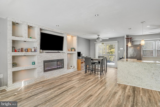 living room featuring a fireplace, hardwood / wood-style floors, and ceiling fan