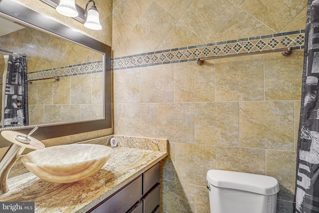 bathroom with toilet, tile walls, and vanity