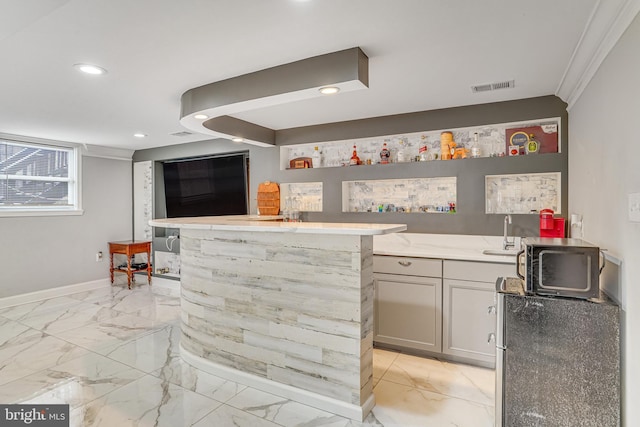 bar featuring sink, gray cabinetry, and ornamental molding