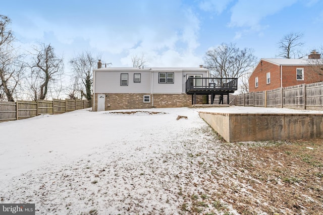 snow covered back of property featuring a wooden deck