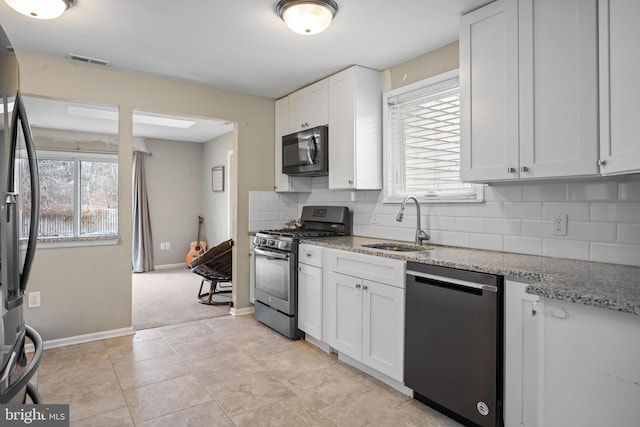 kitchen with sink, appliances with stainless steel finishes, light stone countertops, white cabinets, and decorative backsplash