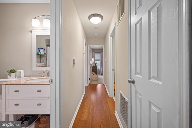 corridor with hardwood / wood-style flooring and sink