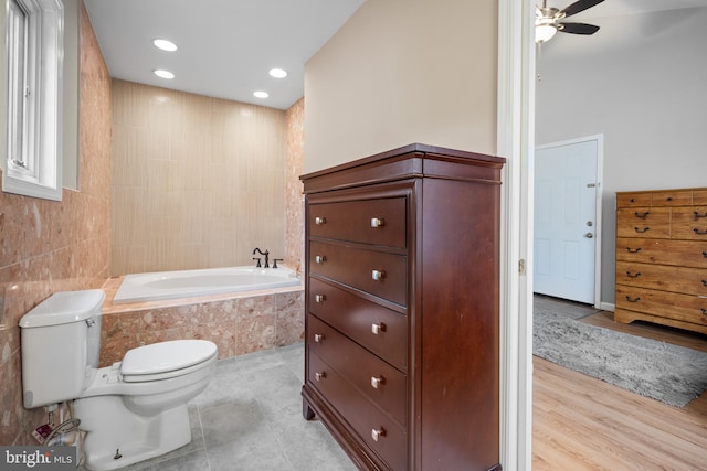 bathroom with toilet, tile walls, ceiling fan, tiled bath, and tile patterned flooring