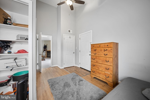 bedroom with a towering ceiling, ceiling fan, and light wood-type flooring