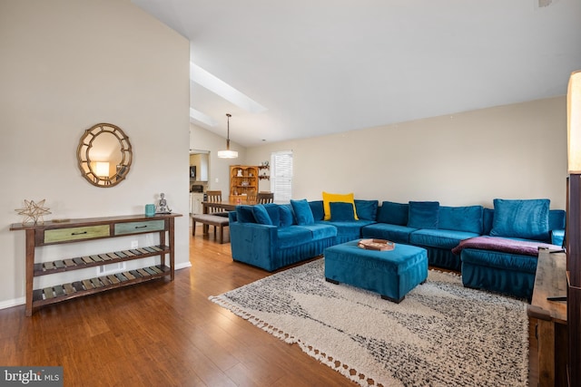 living room featuring vaulted ceiling with skylight and hardwood / wood-style floors