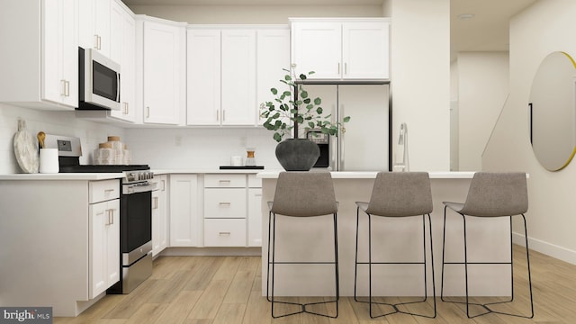 kitchen featuring appliances with stainless steel finishes, white cabinets, a breakfast bar, and a kitchen island