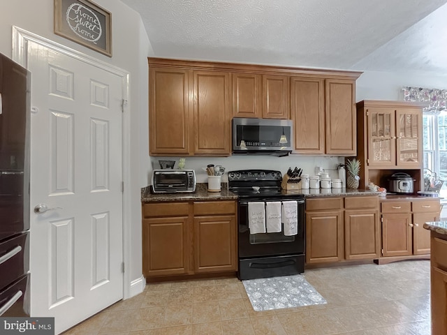 kitchen featuring light tile patterned floors, refrigerator, dark stone countertops, black range with electric stovetop, and a textured ceiling