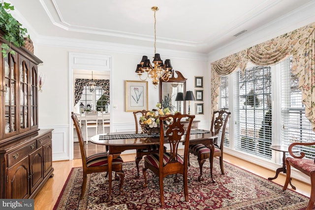 dining area featuring light wood-type flooring, an inviting chandelier, and crown molding