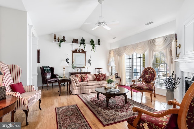 living room featuring ceiling fan, a high end fireplace, light hardwood / wood-style floors, and lofted ceiling