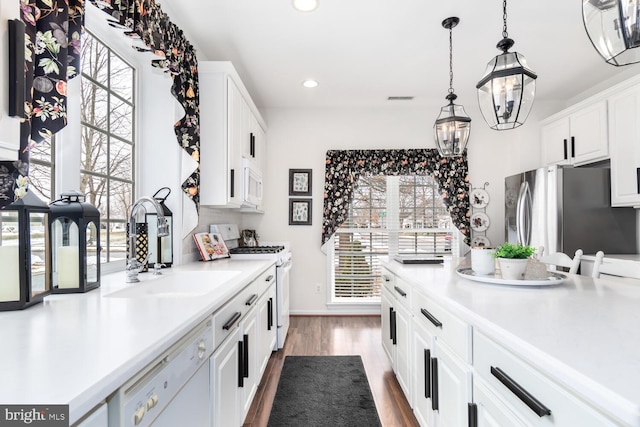 kitchen featuring white appliances, white cabinets, decorative light fixtures, sink, and dark hardwood / wood-style floors