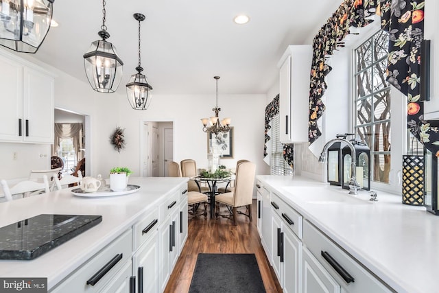 kitchen with decorative light fixtures, sink, white cabinetry, and a chandelier