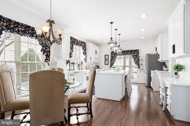 kitchen featuring hanging light fixtures, white cabinets, a kitchen bar, a notable chandelier, and a kitchen island