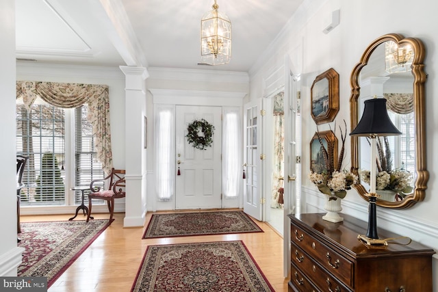 entryway featuring light hardwood / wood-style floors, ornamental molding, plenty of natural light, and an inviting chandelier