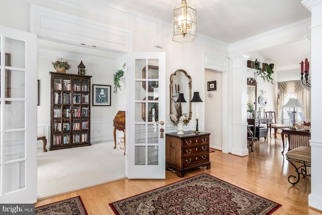 interior space featuring wood-type flooring, french doors, an inviting chandelier, ornamental molding, and decorative columns