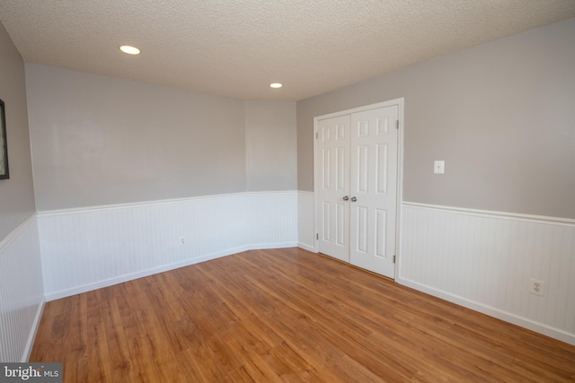 unfurnished room with hardwood / wood-style flooring and a textured ceiling