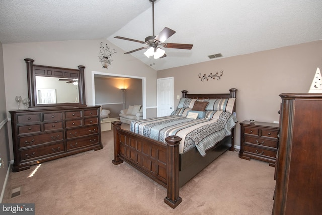 bedroom featuring ceiling fan, vaulted ceiling, light carpet, and a textured ceiling