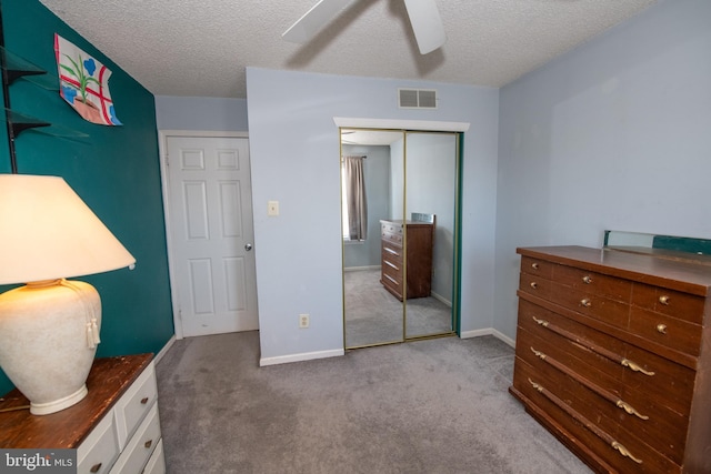 carpeted bedroom with ceiling fan, a closet, and a textured ceiling