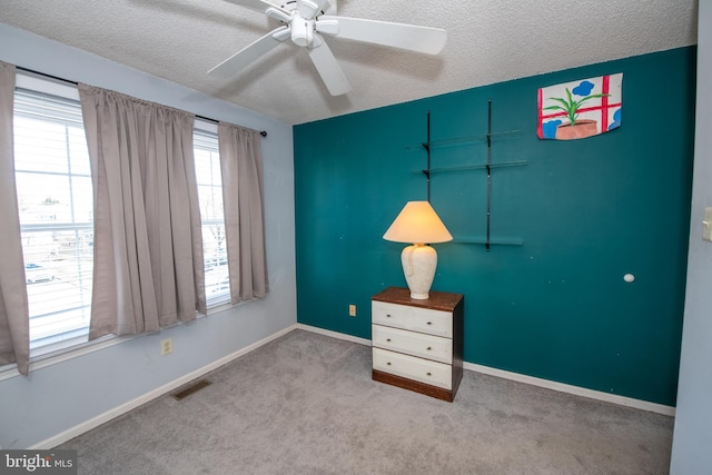 unfurnished bedroom with ceiling fan, carpet, and a textured ceiling