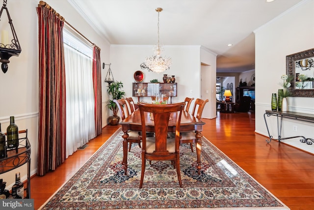 dining room with a notable chandelier, hardwood / wood-style flooring, and ornamental molding