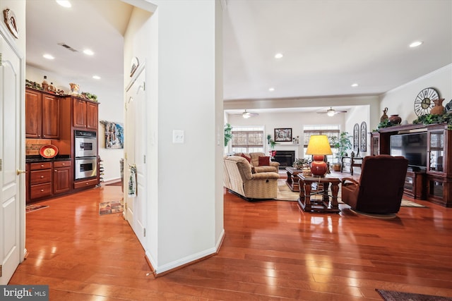 interior space with crown molding, dark hardwood / wood-style floors, double oven, and ceiling fan