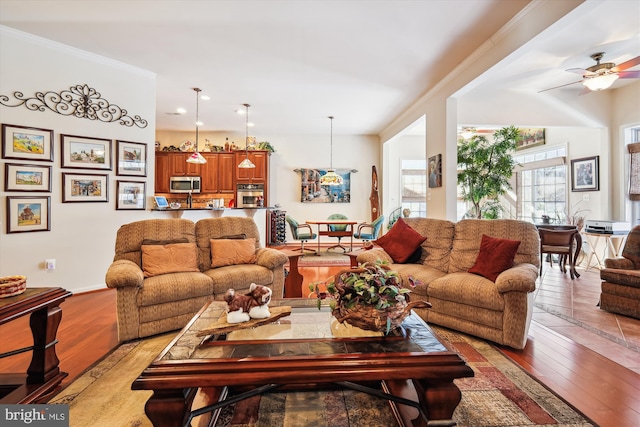 living room featuring crown molding, light wood-type flooring, and ceiling fan