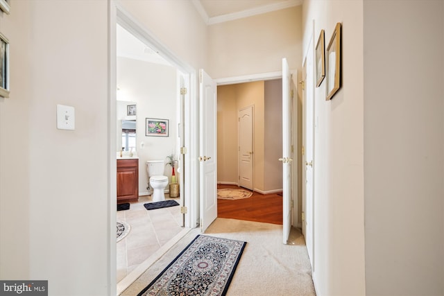 corridor featuring ornamental molding and light carpet