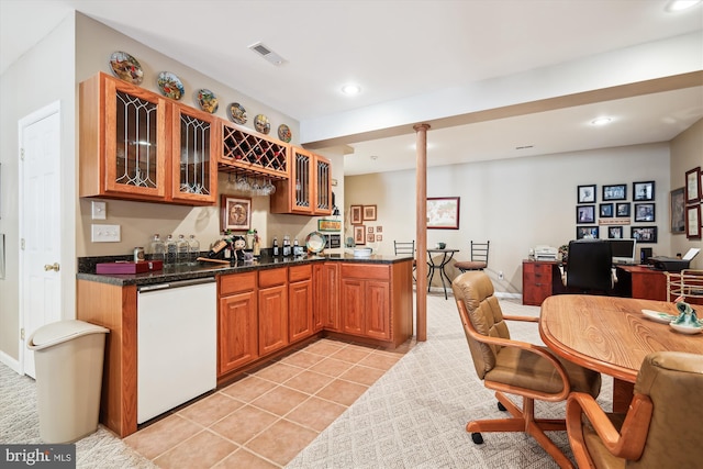 kitchen featuring kitchen peninsula, dishwasher, sink, light tile patterned floors, and dark stone countertops