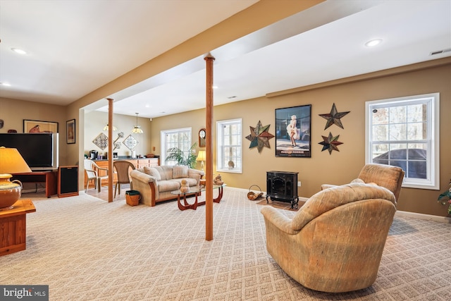 living room with carpet floors, a wood stove, and ornate columns