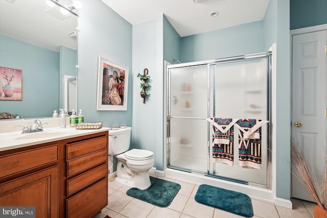 bathroom featuring toilet, a shower with door, vanity, and tile patterned flooring