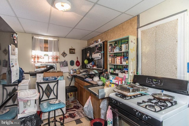 kitchen featuring white gas range and a drop ceiling