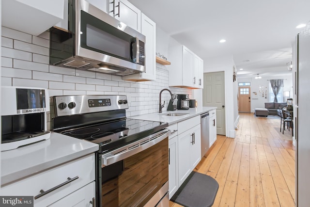 kitchen featuring stainless steel appliances, sink, white cabinets, and light hardwood / wood-style floors