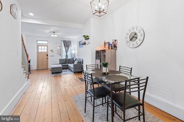 dining area with wood-type flooring and a notable chandelier