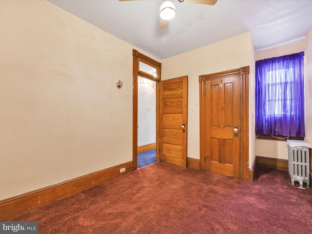 unfurnished bedroom with ceiling fan, radiator, and dark colored carpet