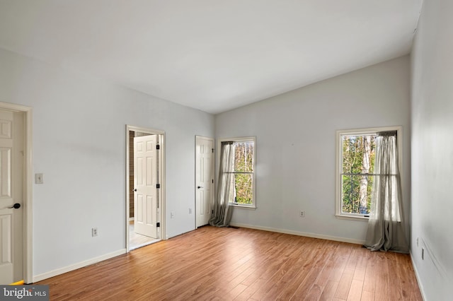 unfurnished bedroom featuring lofted ceiling and light hardwood / wood-style floors