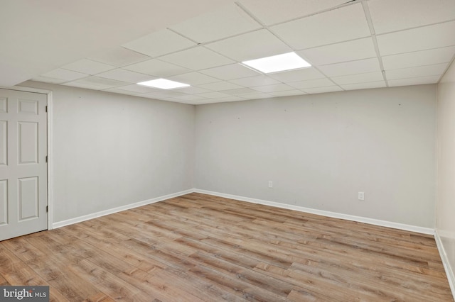 empty room with a drop ceiling and light hardwood / wood-style flooring