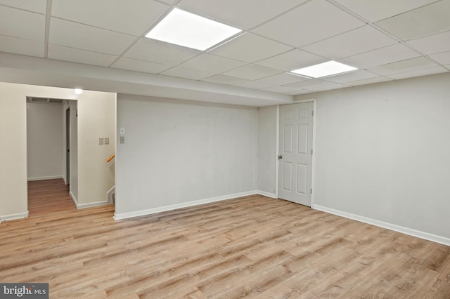 basement with a paneled ceiling and light hardwood / wood-style flooring