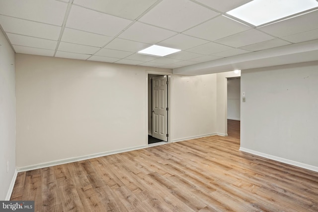 basement with light hardwood / wood-style flooring and a paneled ceiling