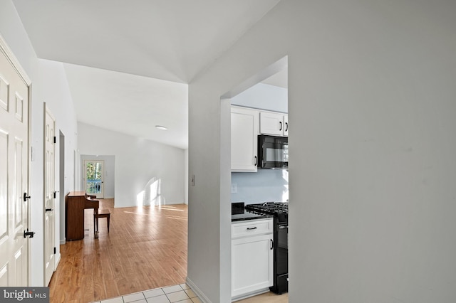 corridor featuring vaulted ceiling and light tile patterned floors