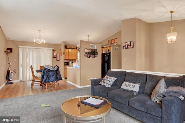 living room with vaulted ceiling, a chandelier, and light hardwood / wood-style floors