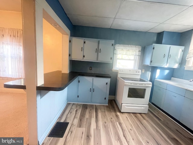 kitchen featuring light wood-type flooring, a drop ceiling, electric range, and white cabinetry